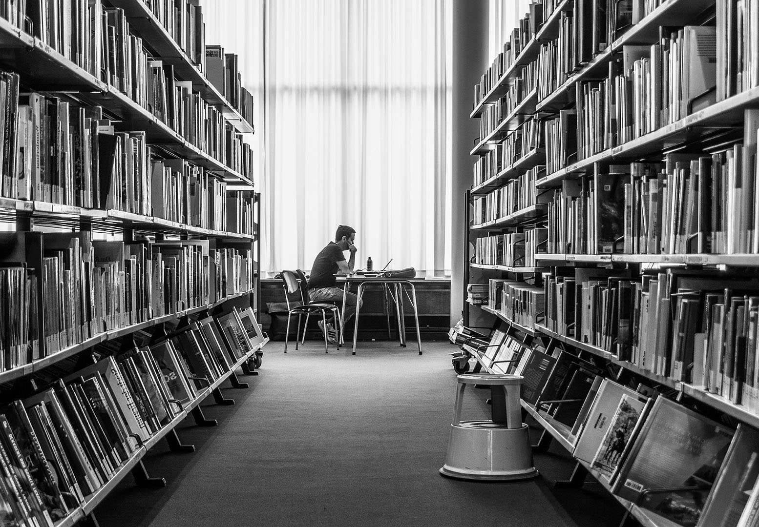 Photo d'un homme assi sur une chaise dans une bibliothèque